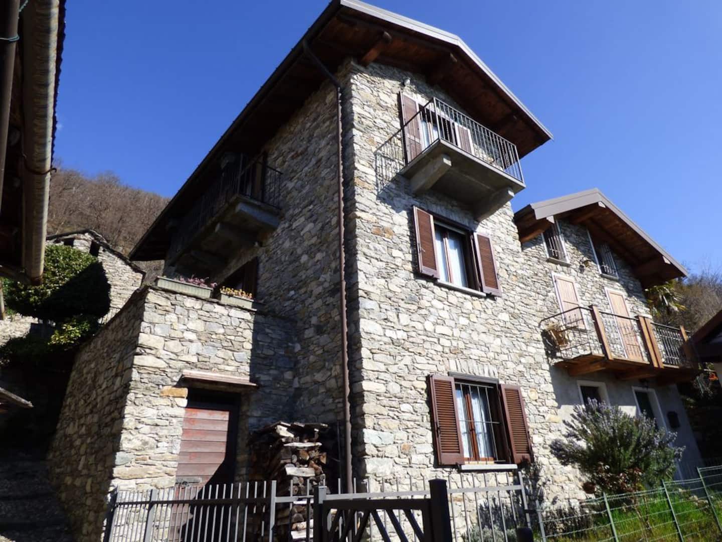 Gammelt steinhus i Montemezzo under blå himmel