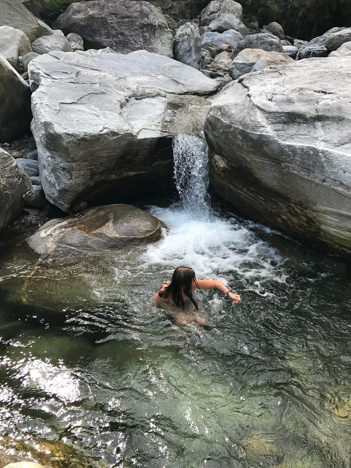 Bading i en klar kulp under en liten foss