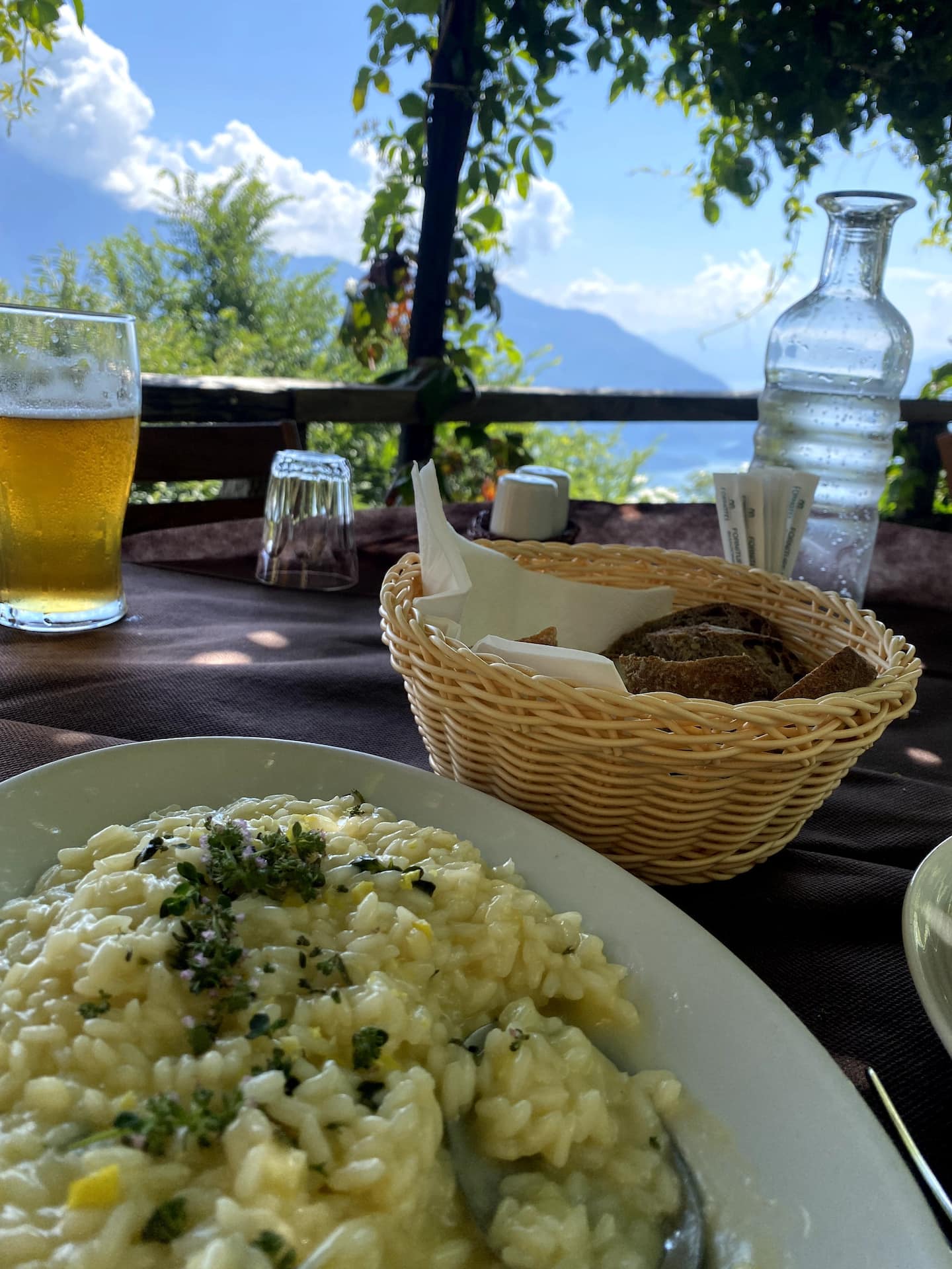 Risotto, brød og et glass øl på en restaurantterrasse med utsikt